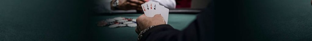 Een man zit aan een goktafel en kijkt naar zijn kaarten